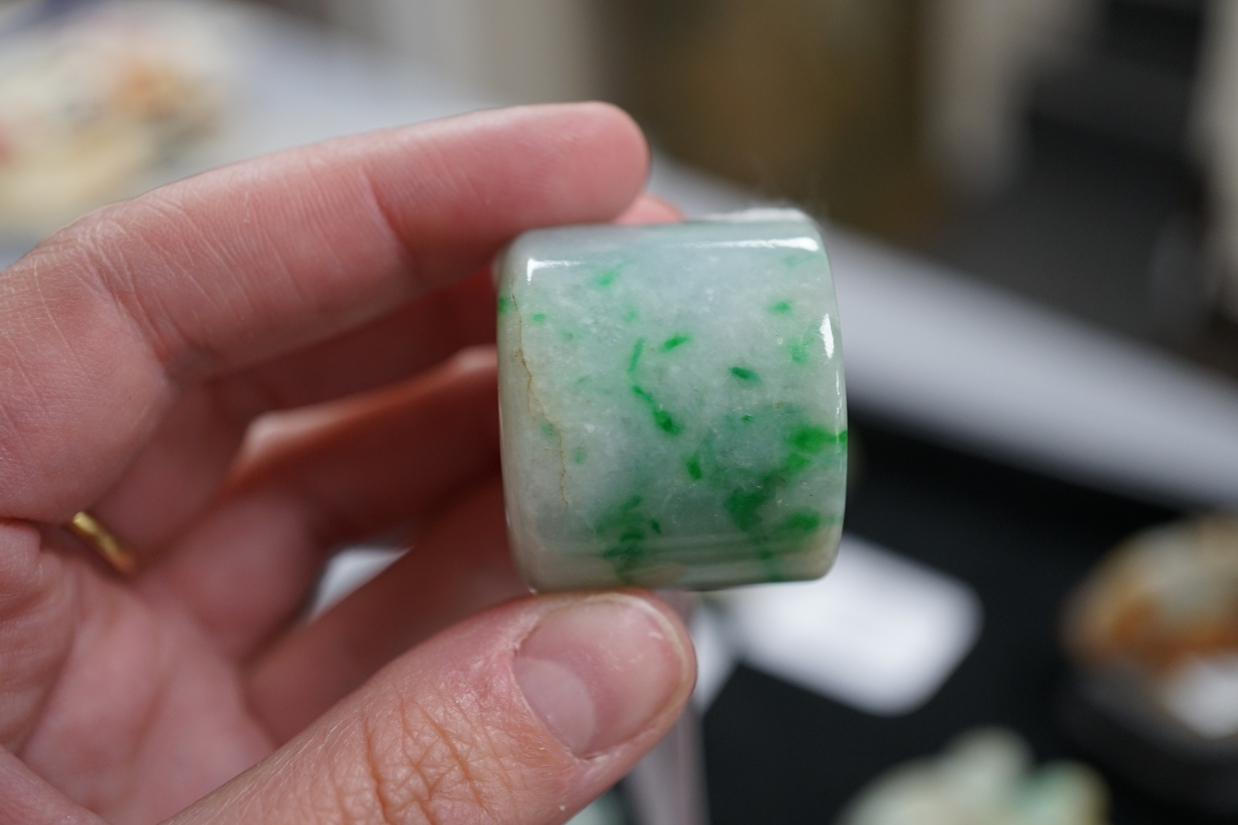A Chinese jadeite archer's thumb ring, wood stand and cover, 19th century